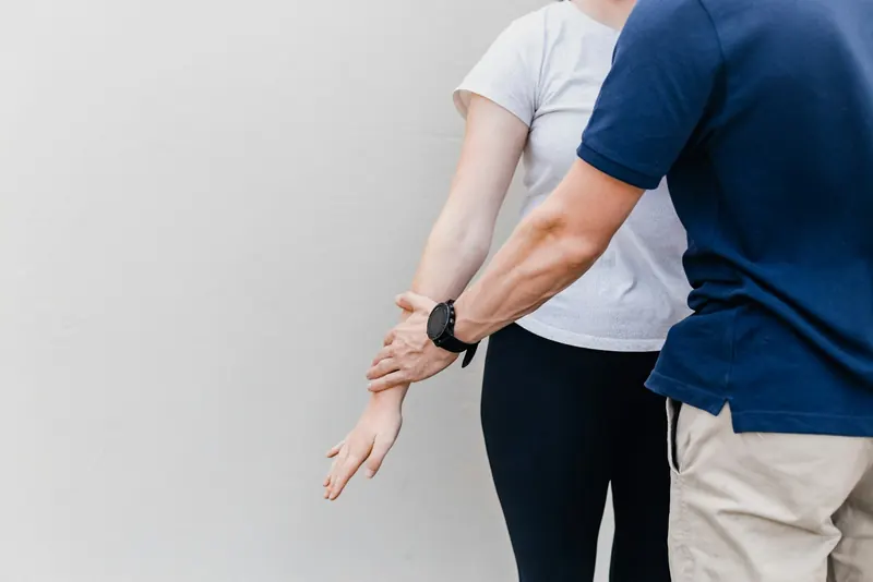 Practitioner guiding a client's arm through a manual muscle test