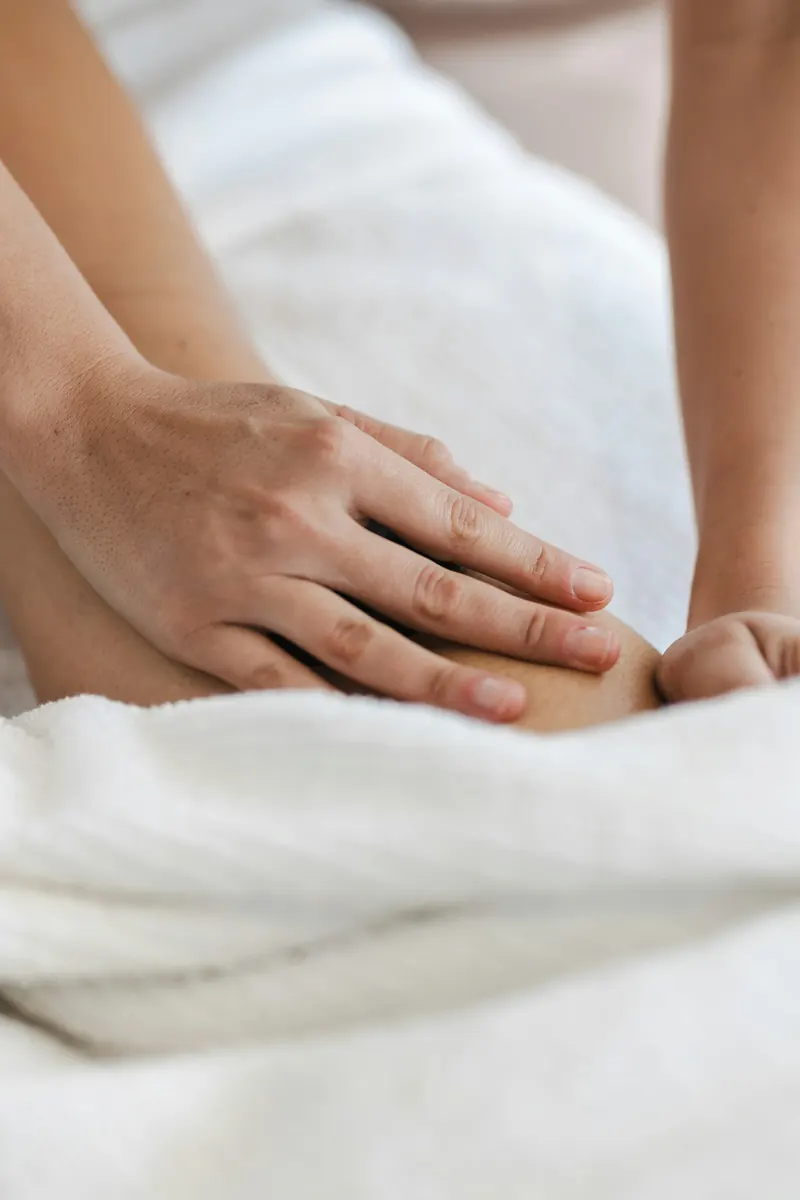 Therapist applying focused pressure point release to a client's calf on a treatment table